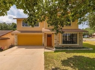 A house with a yellow garage door is surrounded by greenery.