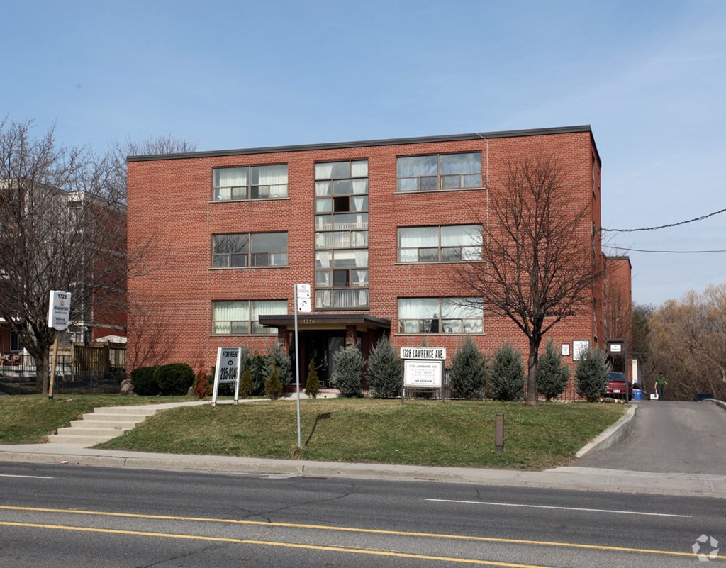 A red brick building with a sign that says "Sale Here" in front of it.