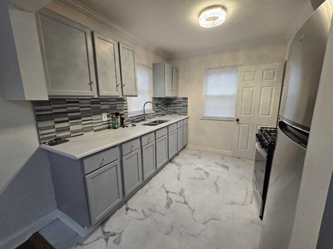 A kitchen with a marble floor and a stainless steel dishwasher.