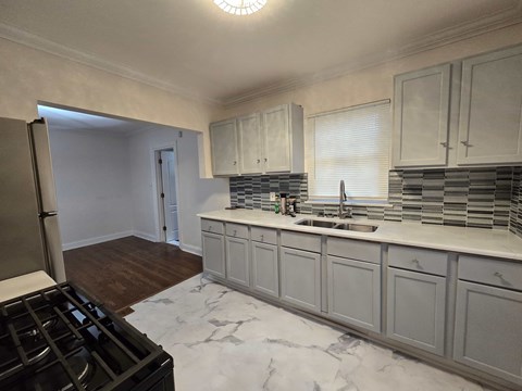 A kitchen with a black stove top oven and white cabinets.