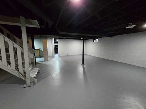 A spacious, empty room with a staircase on the left side.