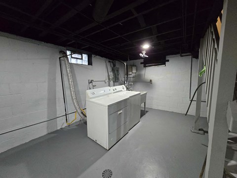 A white industrial sink is in a room with a grey floor and walls.