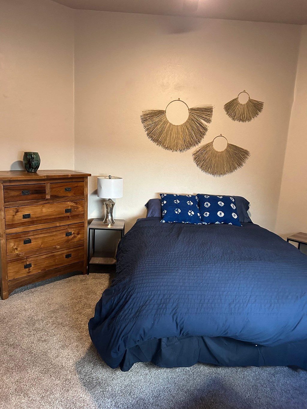 A bedroom with a bed, nightstand, and wall decor.