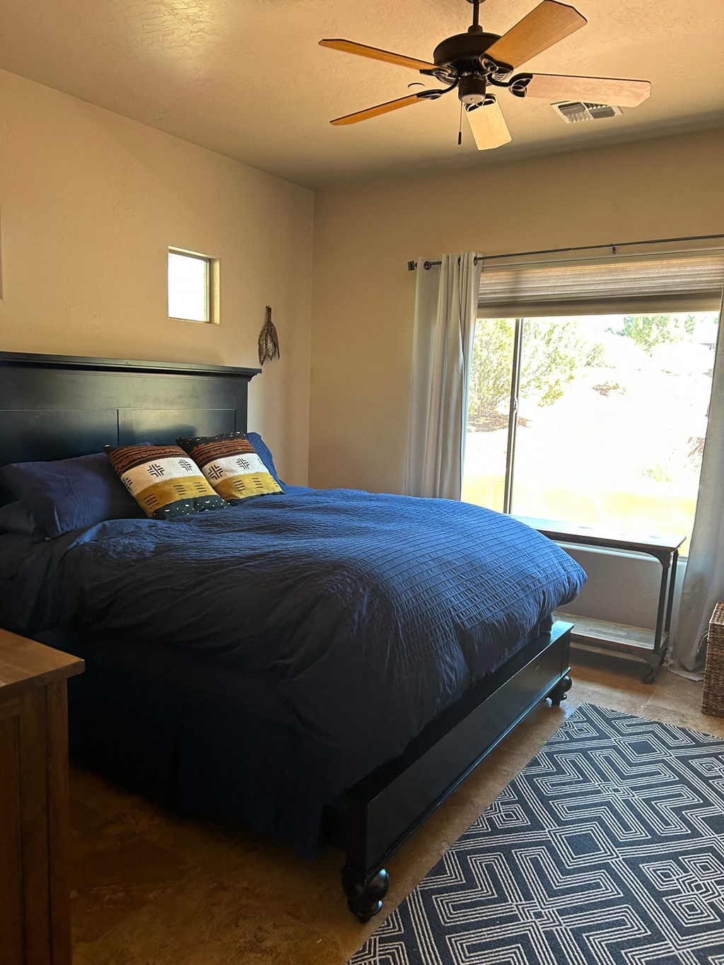 A bedroom with a bed, a ceiling fan, and a window.