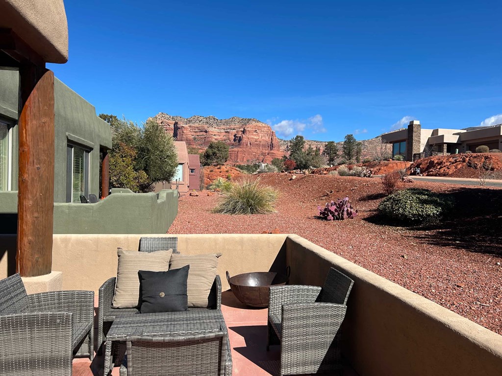 A patio with chairs and a table overlooks a desert landscape.
