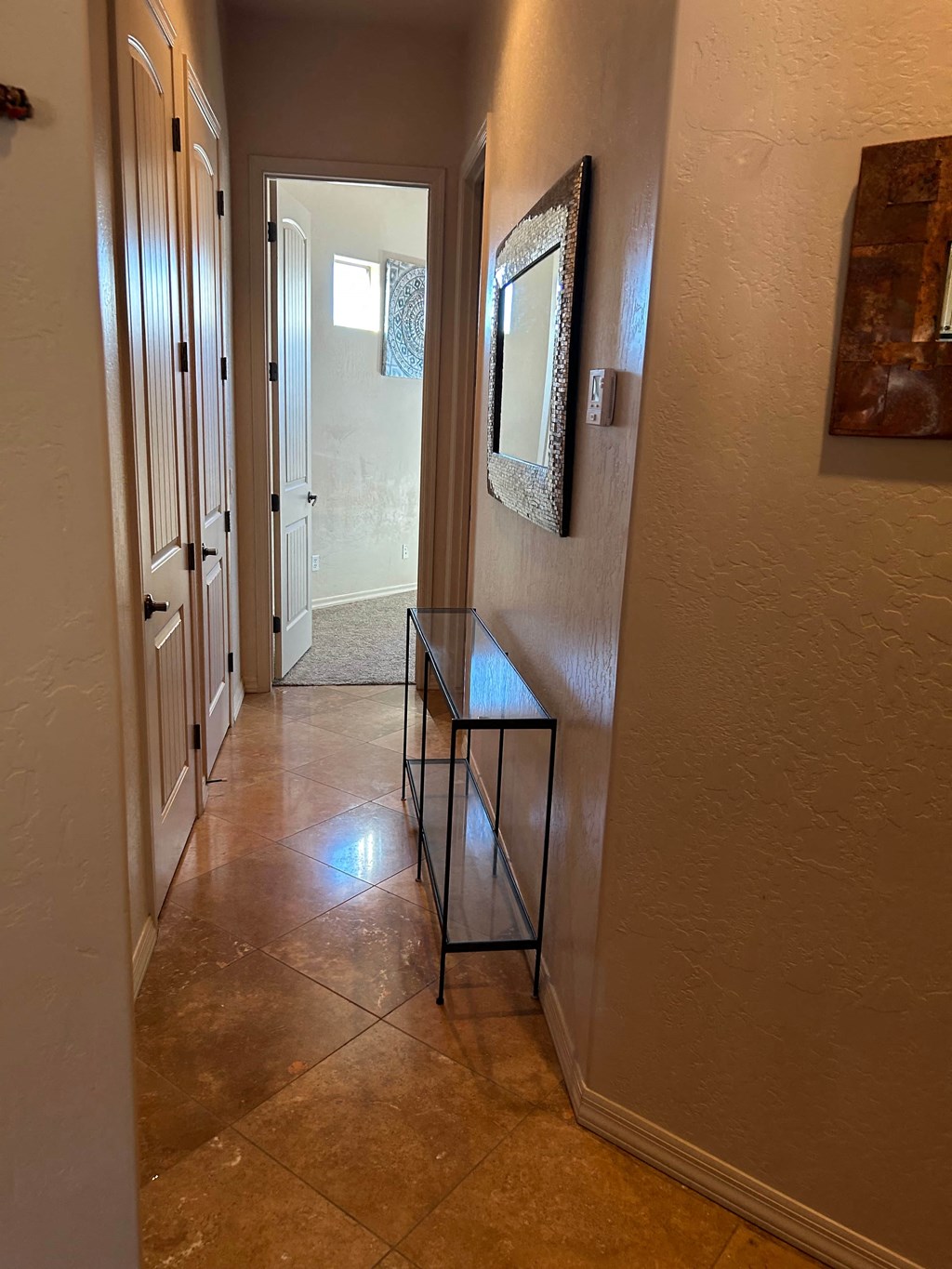 A hallway with a table and a mirror on the wall.