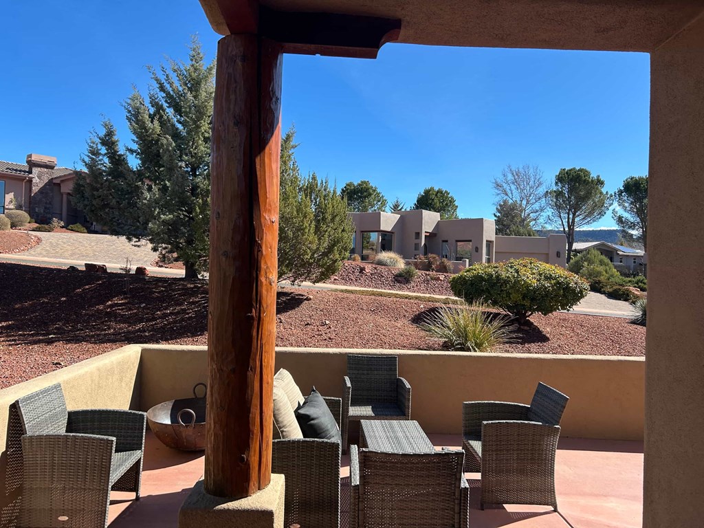 A wooden pole stands in the middle of a patio with wicker chairs around it.