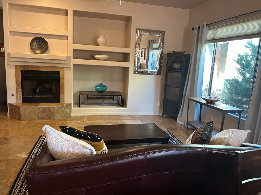 A living room with a fireplace and a brown couch.