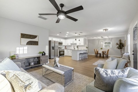 A modern living room with a grey sofa set and a ceiling fan.