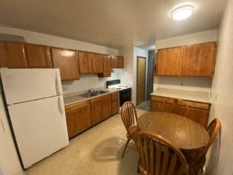 A kitchen with a white refrigerator and wooden cabinets.