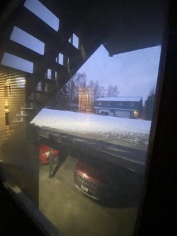 A car is parked in front of a building with snow on the ground.