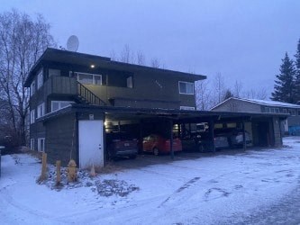 A house with a garage full of cars in the snow.