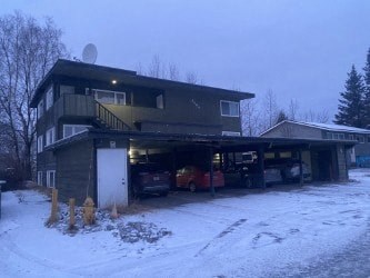 A house with a garage full of cars in the snow.