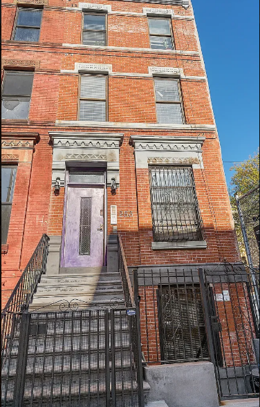 A red brick building with a purple door and a black iron fence.