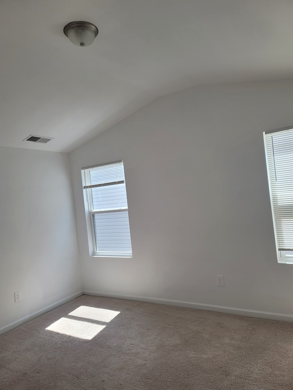 A room with a window and a carpeted floor.