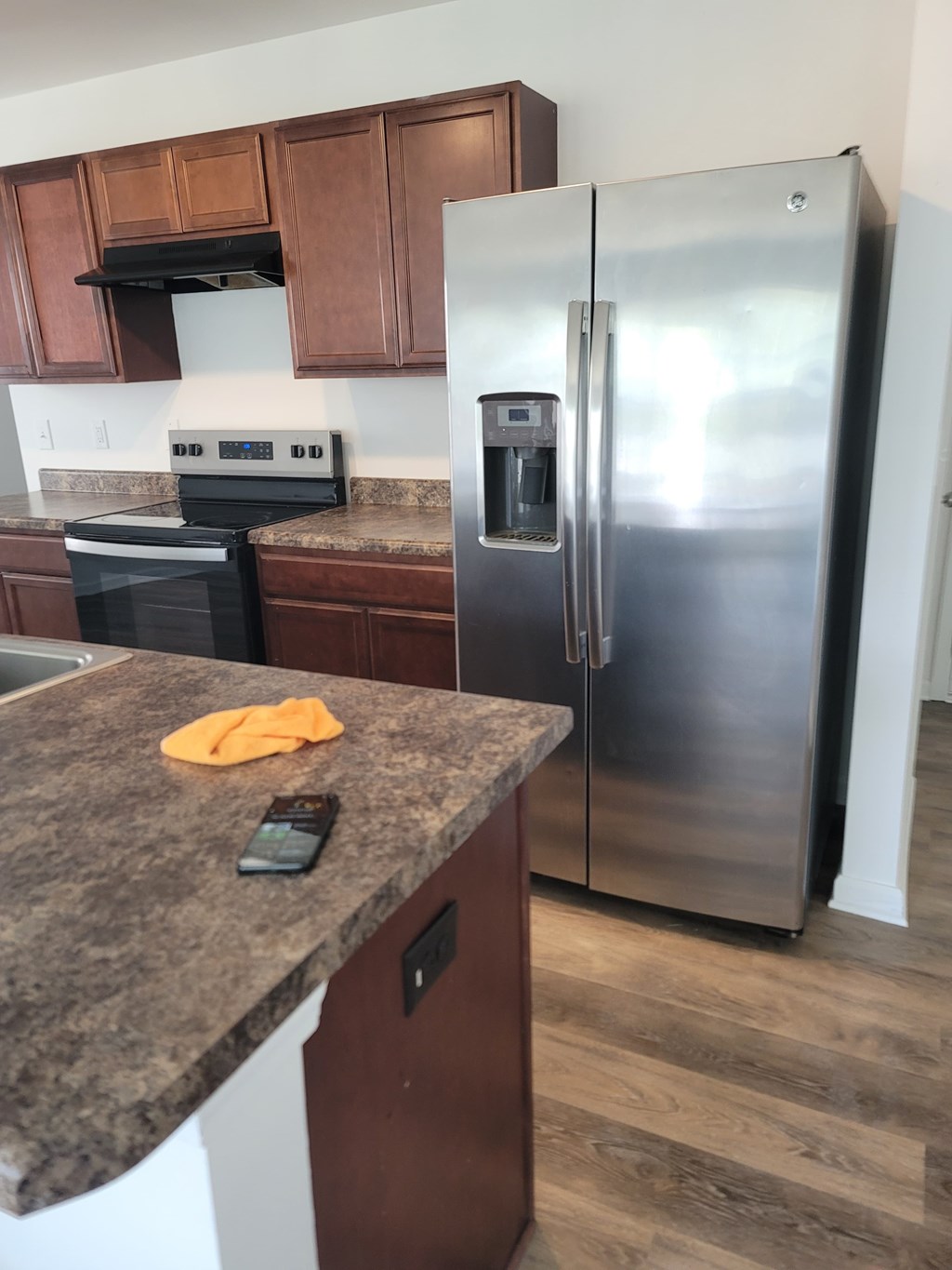 A kitchen with a granite counter top and a stainless steel refrigerator.