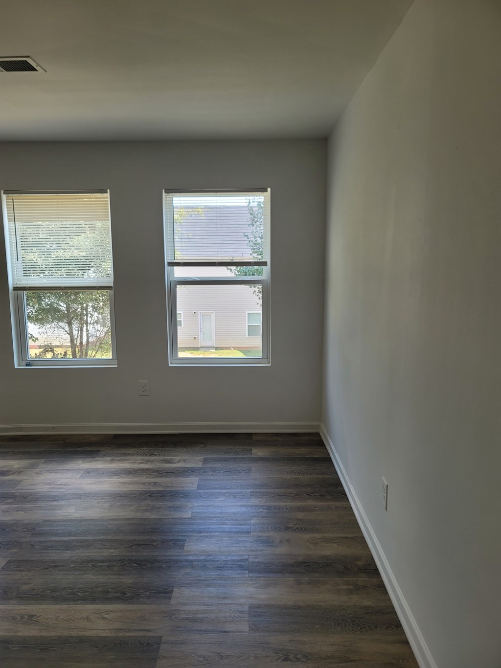 A room with a window and a wooden floor.