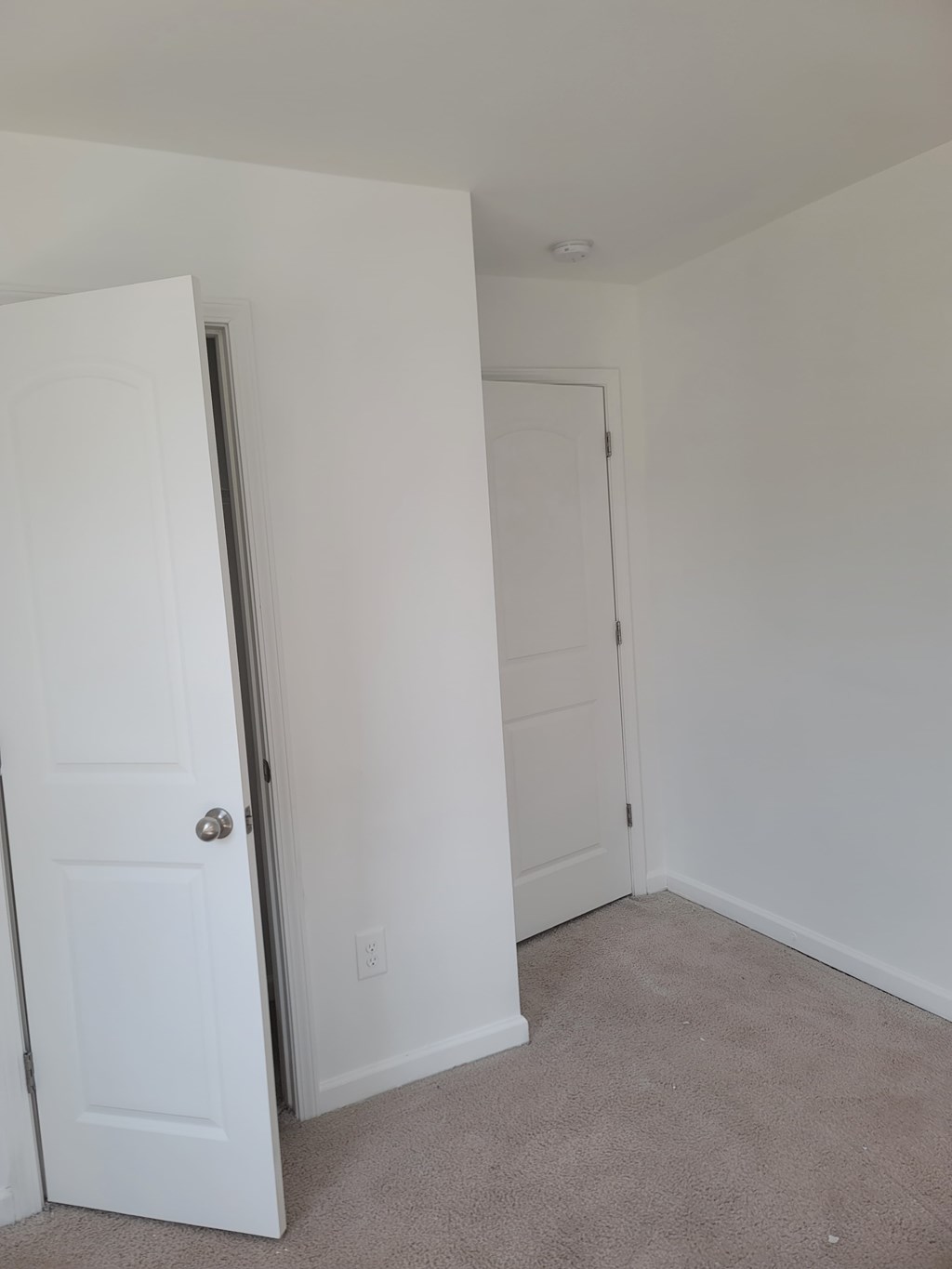 A white door is open to a carpeted room.