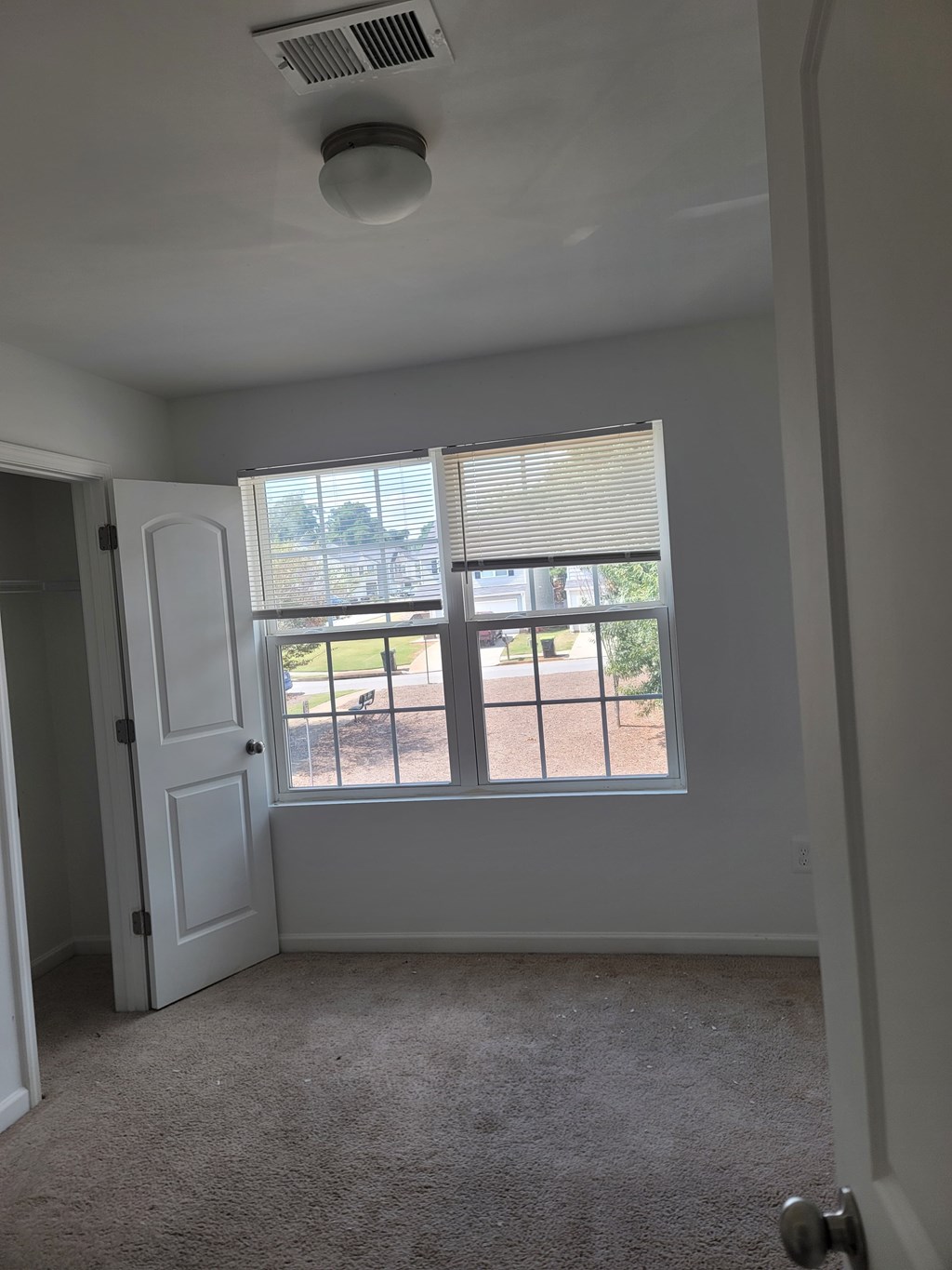 A room with a door and a window overlooking a fence.