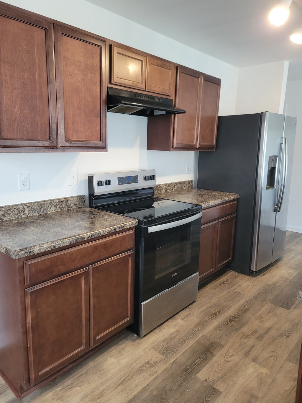 A kitchen with wooden cabinets and a black fridge.
