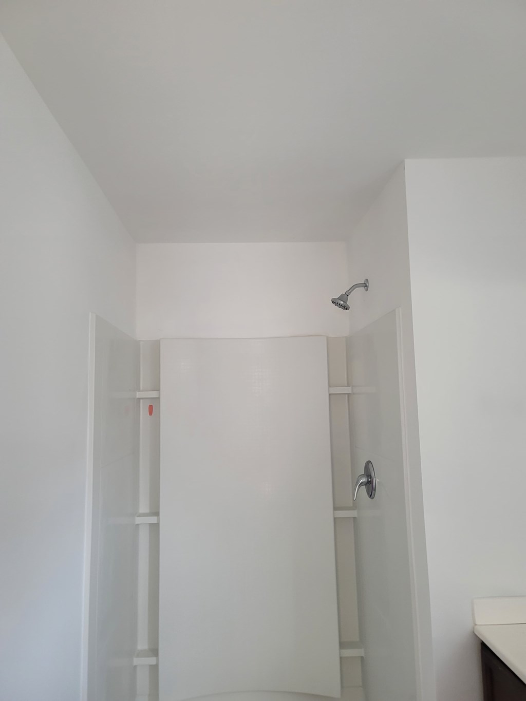 A white door with a silver handle is in a white room.
