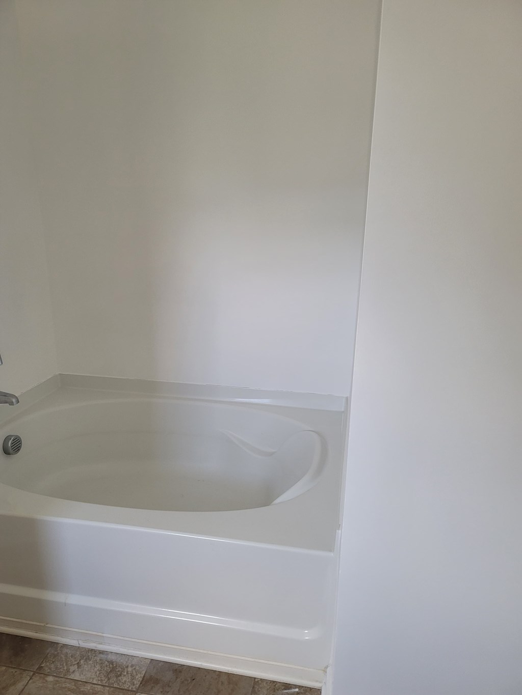 A white bathtub in a bathroom with a white wall.