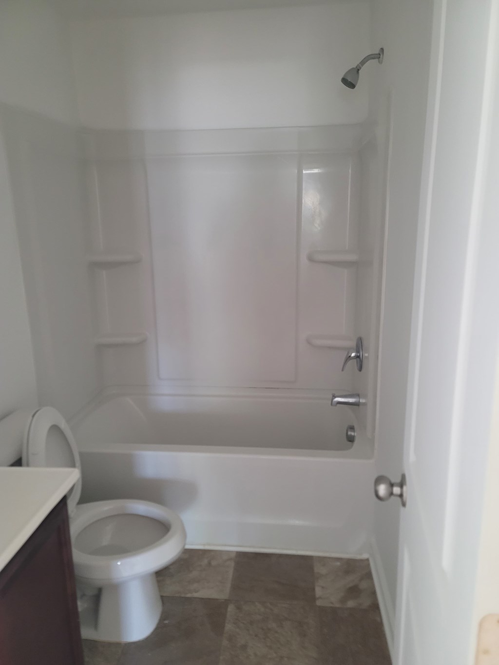 A white toilet sits in a bathroom next to a walk-in shower.