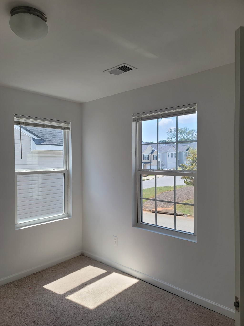 A room with two windows and a carpeted floor.