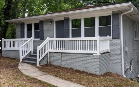 A small house with a porch and a white railing.