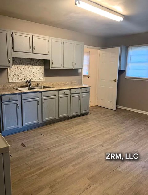 A kitchen with wooden floors and cabinets.