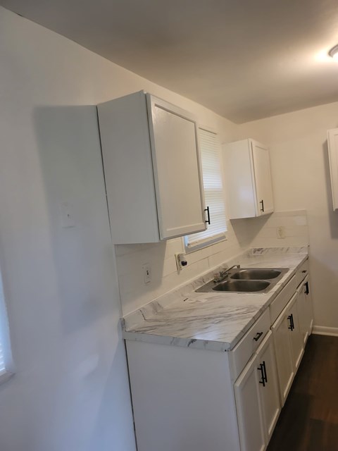 A kitchen with white cabinets and a marble countertop.
