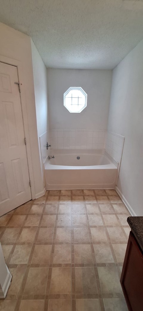 A bathroom with a tiled floor and a round window.