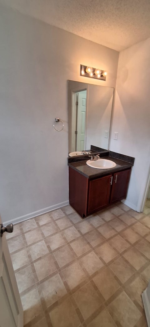 A bathroom with a brown vanity and a white wall.