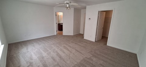 A room with carpeted floor and a ceiling fan.