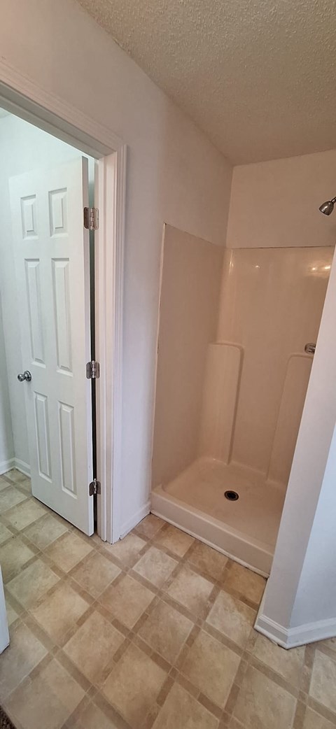 A bathroom with a white door and a tiled floor.