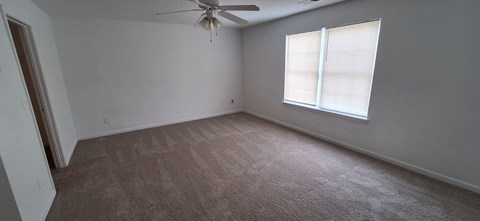 A room with a ceiling fan and a window with blinds.