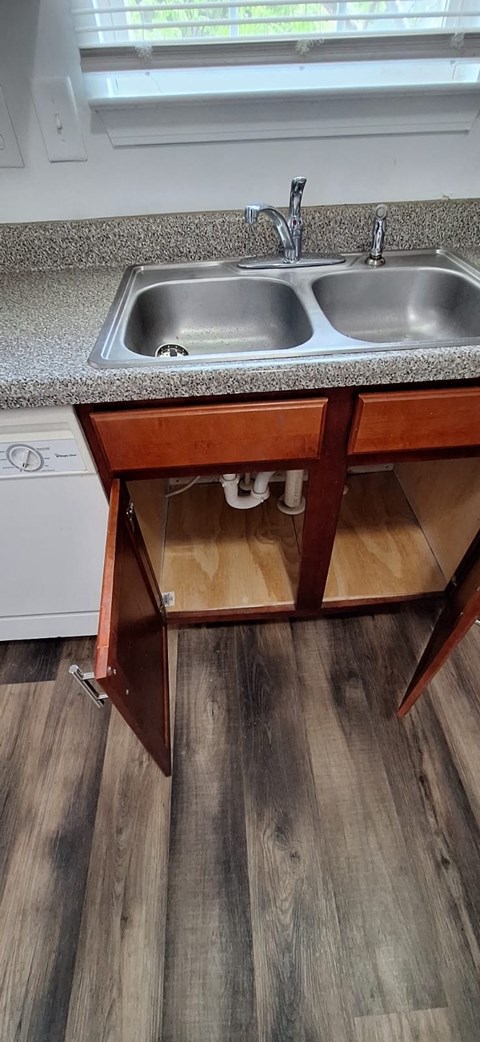 A kitchen with a sink and a wooden floor.