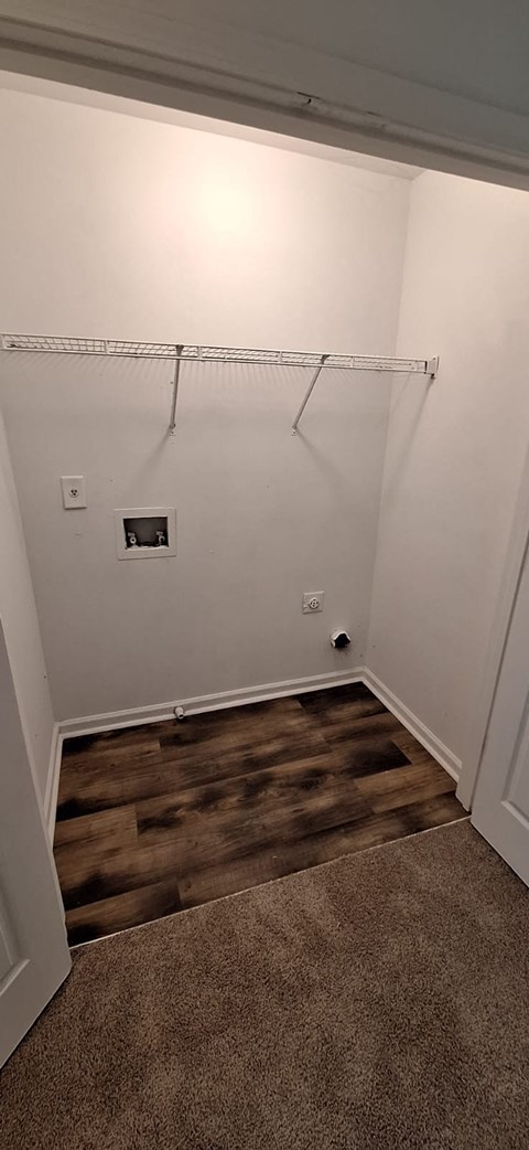 A room with a white wall and a brown carpet.