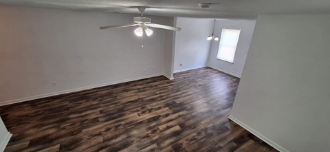 A room with wooden flooring and a ceiling fan.