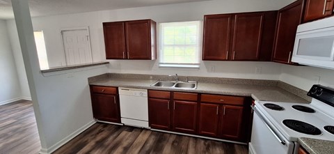 A kitchen with brown cabinets and white appliances.