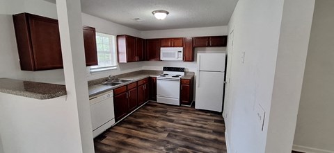 A kitchen with white appliances and brown cabinets.