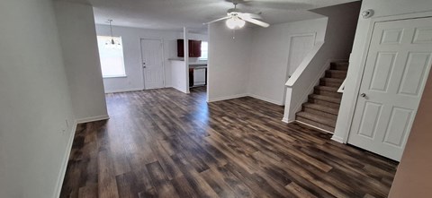 A room with wooden floors and a staircase leading to another room.
