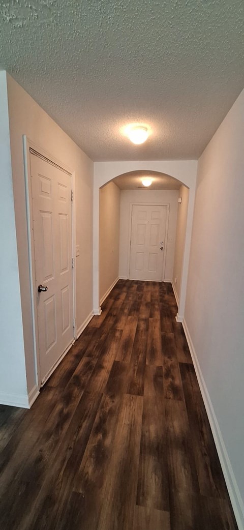 A hallway with wood flooring and white walls.