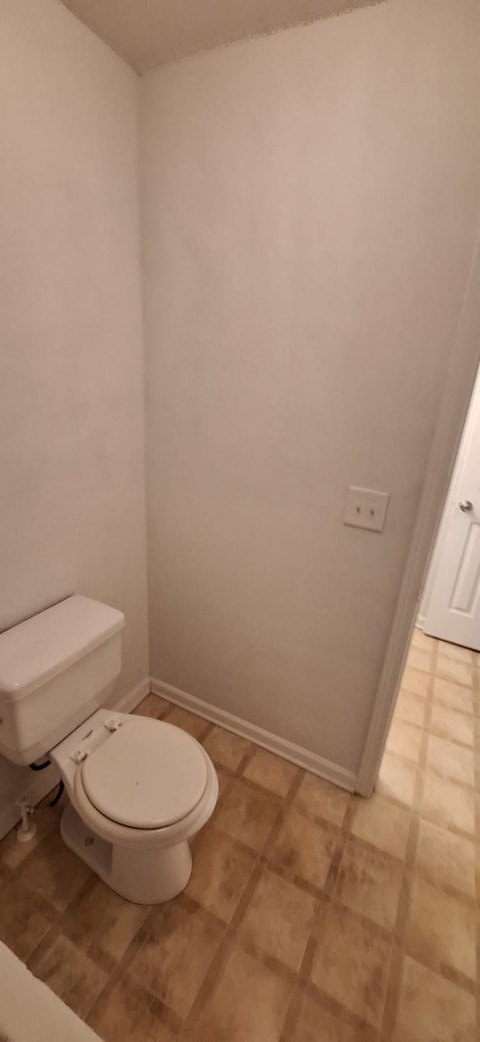 A white toilet in a small bathroom with a tiled floor.