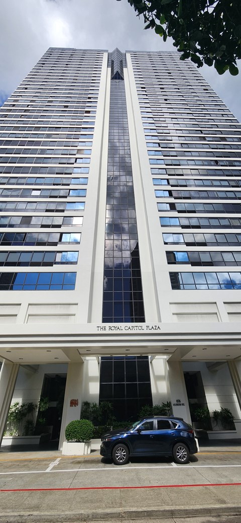 A tall white building with a black car parked in front.