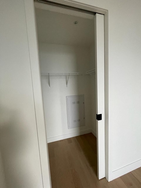 A white door is open to a room with a wooden floor.