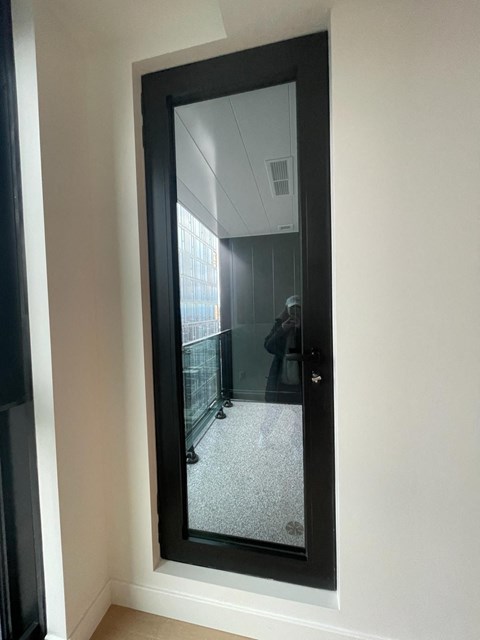 A mirror reflects a room with a person standing in it.