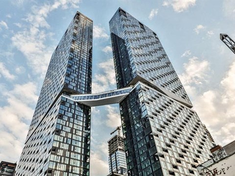 Three tall buildings with glass windows and a bridge connecting them.