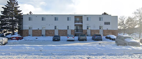 A white building with a parking lot in front of it.