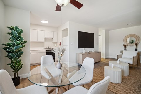 A modern living room with a glass table and white chairs.